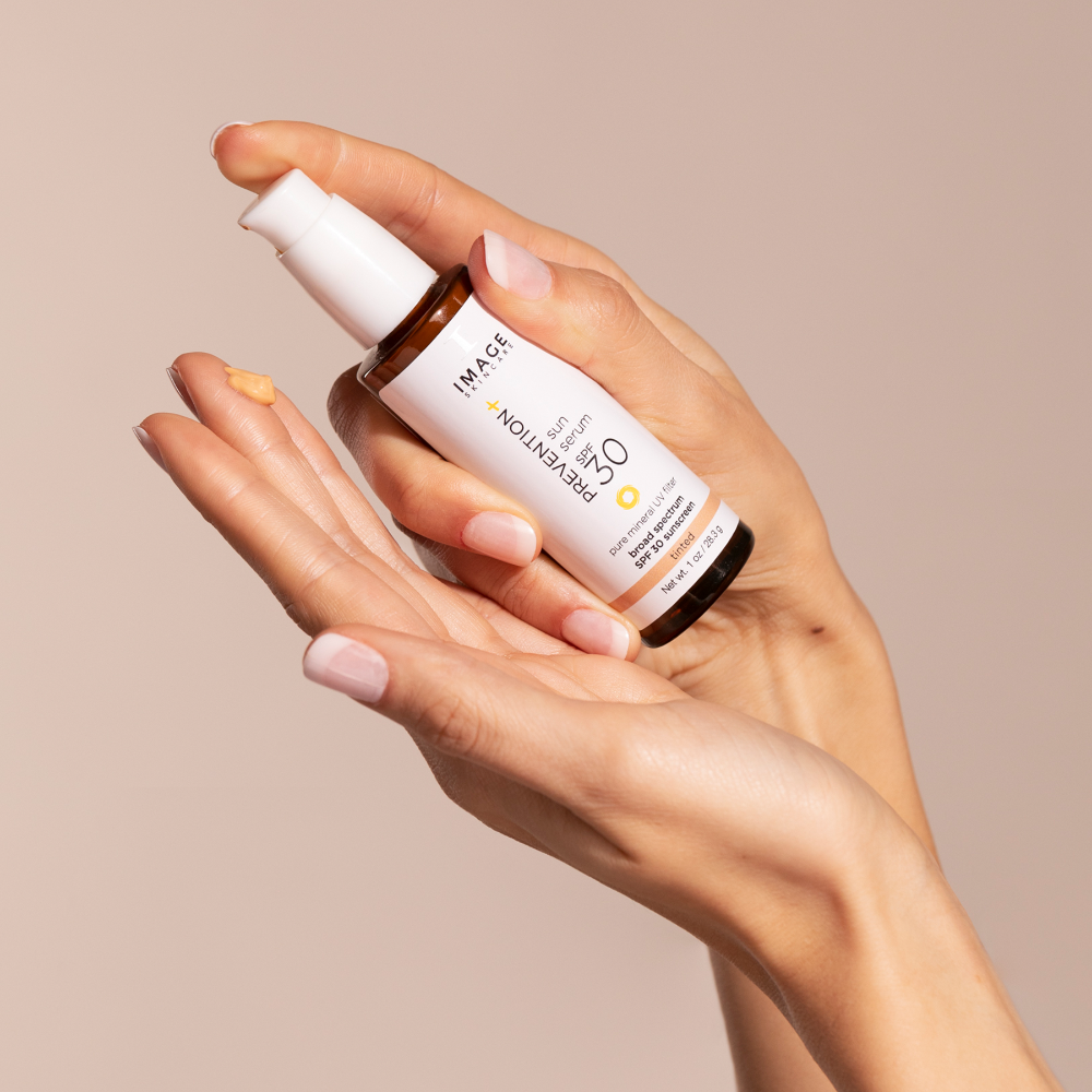 Hand holding a skincare bottle with a beige background